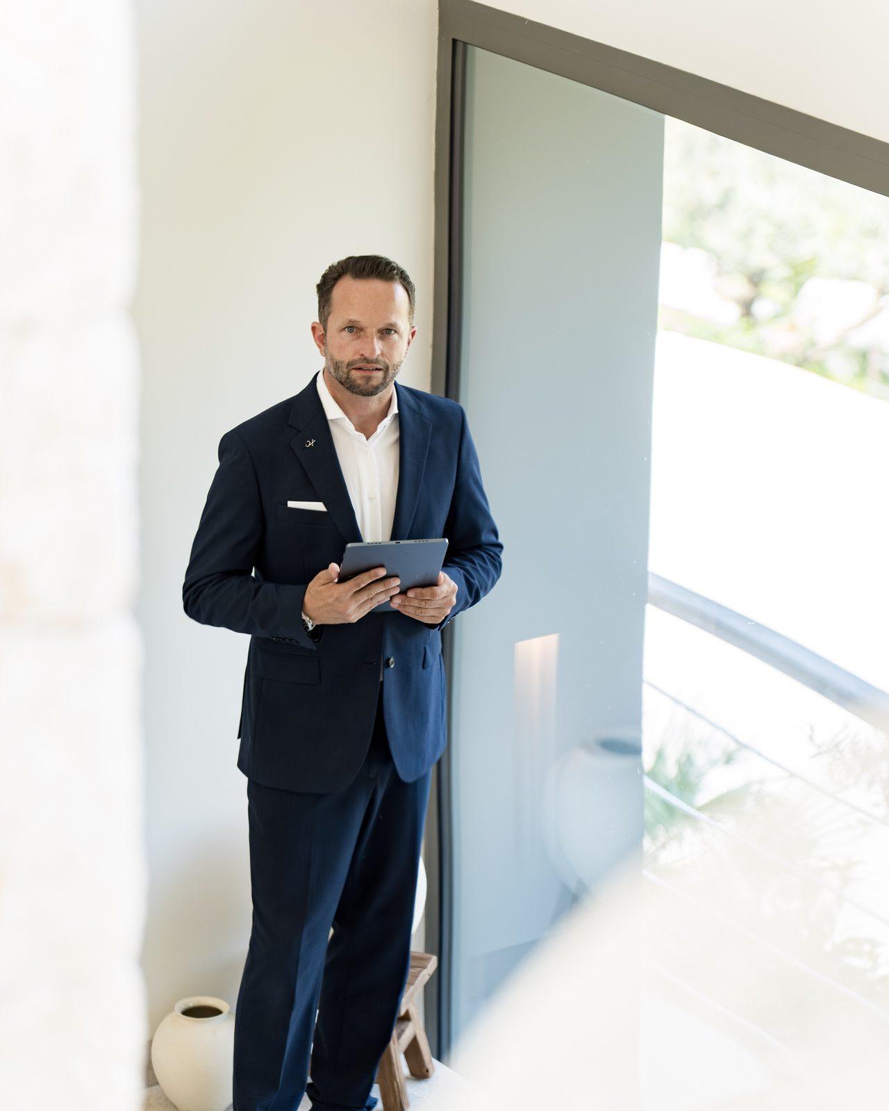 Daniel Rudolf — Founder-Portrait in einer Luxusvilla auf Mallorca, navy Anzug, direkter Blick.