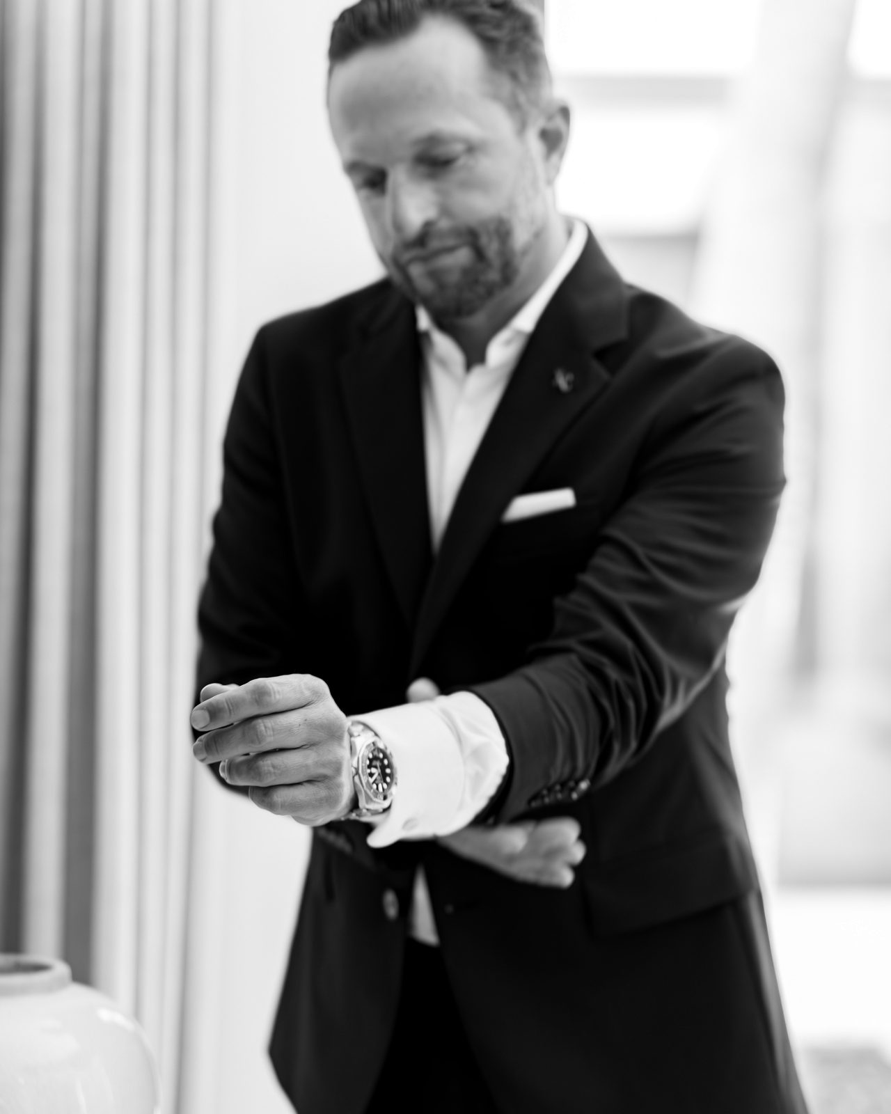 Daniel Rudolf — Schwarz-Weiß-Aufnahme, richtet die Uhr am Manschettenärmel.